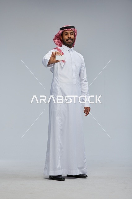 رجل سعودي يحمل بطاقة بيضاء فارغة في الاستوديو