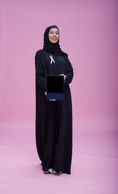 امرأة سعودية تحمل جهازاً لوحياً للتوعية بسرطان الثدي
