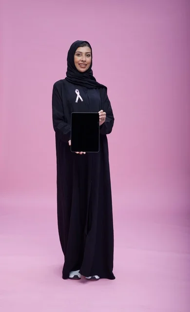 امرأة سعودية مع جهاز لوحي وشريط التوعية بسرطان الثدي