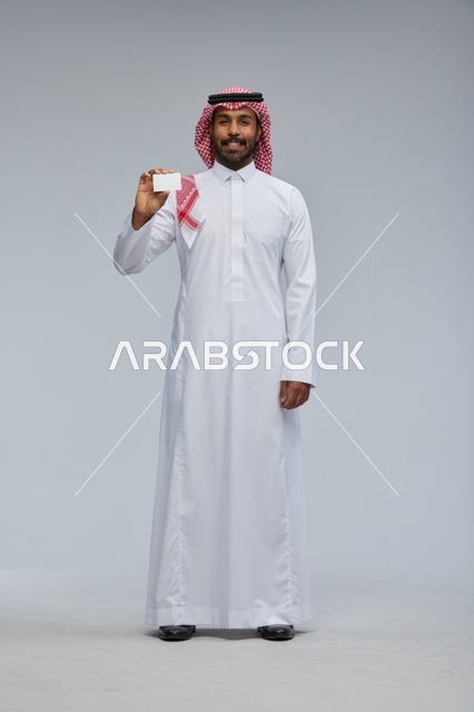 رجل سعودي يحمل بطاقة عمل فارغة بخلفية رمادية