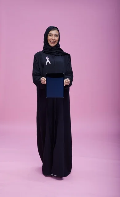 امرأة سعودية مع شريط سرطان الثدي تمسك بجهاز لوحي