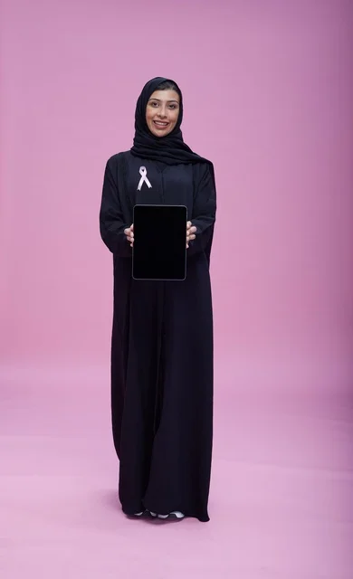 امرأة سعودية تحمل تابلت مع شريط سرطان الثدي
