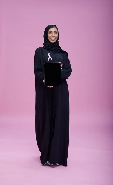 امرأة سعودية تحمل جهاز لوحي مع شريط التوعية بالسرطان