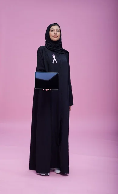 Saudi Woman Holding Tablet with Breast Cancer Ribbon