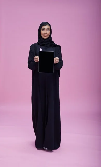 امرأة سعودية تحمل جهازاً لوحياً للتوعية بسرطان الثدي