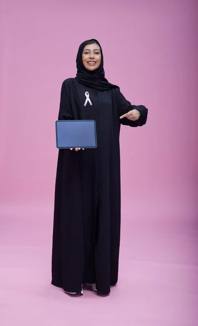 امرأة سعودية تحمل جهازاً لوحياً للتوعية بسرطان الثدي