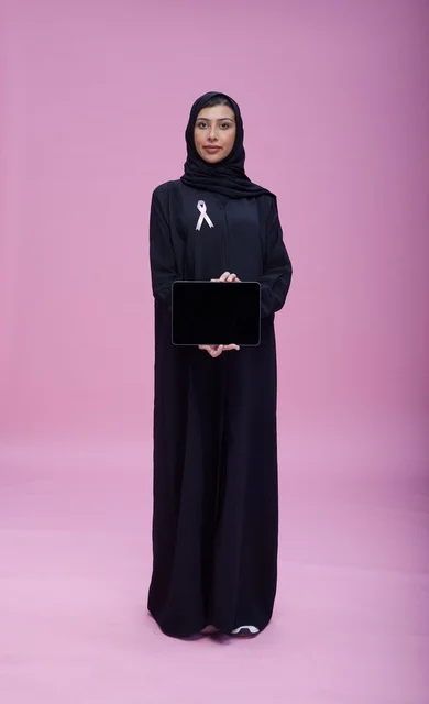 امرأة سعودية تحمل تابلت مع شريط سرطان الثدي