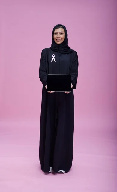 امرأة سعودية تحمل جهازاً لوحياً وشريط التوعية