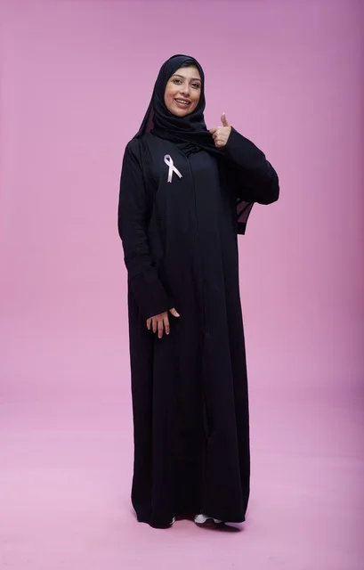 امرأة سعودية مع شريط التوعية بسرطان الثدي بخلفية وردية