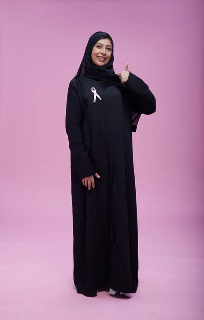 امرأة سعودية ترتدي شريط التوعية بسرطان الثدي بخلفية وردية