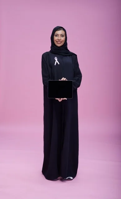 امرأة سعودية مع جهاز لوحي وشريط التوعية بسرطان الثدي
