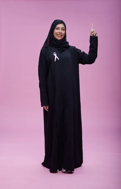 امرأة سعودية بشريط التوعية بسرطان الثدي بخلفية وردية