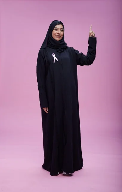 امرأة سعودية مع شريط سرطان الثدي بخلفية وردية