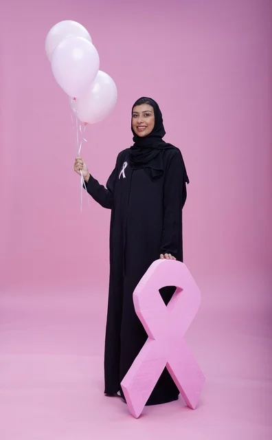 امرأة سعودية تحمل بالونات ورمز الشريط الوردي للتوعية