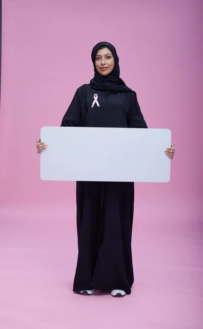 Saudi woman holding blank banner for breast cancer awareness