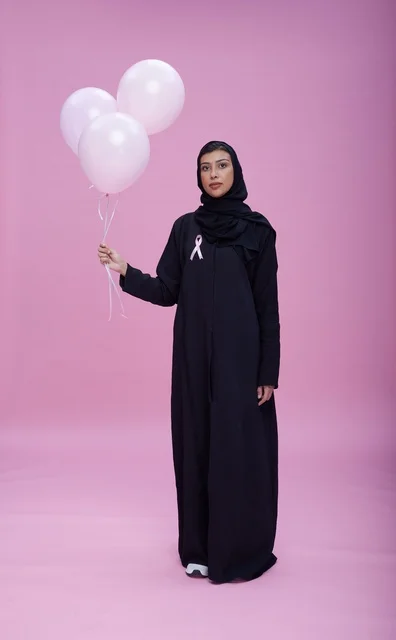 امرأة سعودية تحمل بالونات التوعية بسرطان الثدي