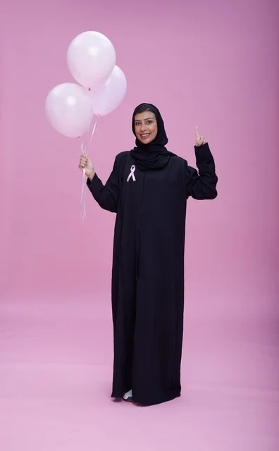 امرأة سعودية تحمل بالونات وردية للتوعية بسرطان الثدي