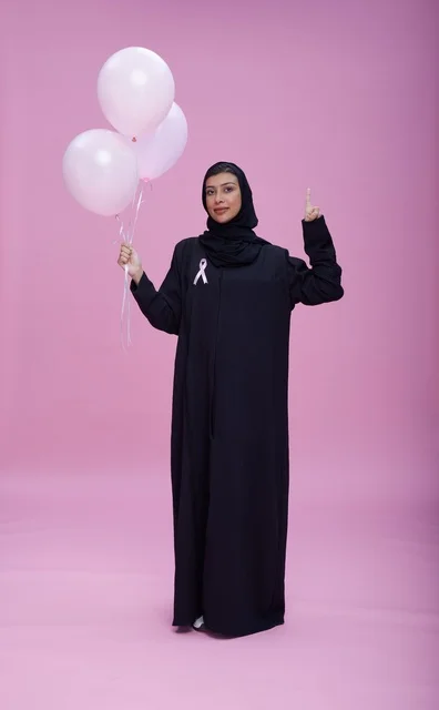 امرأة سعودية مع شريط وبالونات التوعية بسرطان الثدي