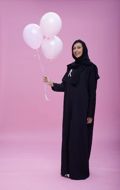 امرأة سعودية تحمل بالونات وردية للتوعية بسرطان الثدي