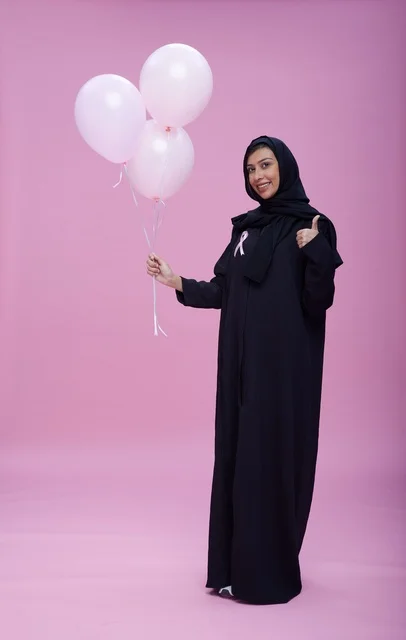 امرأة سعودية تحمل الشريط الوردي وبالونات للتوعية