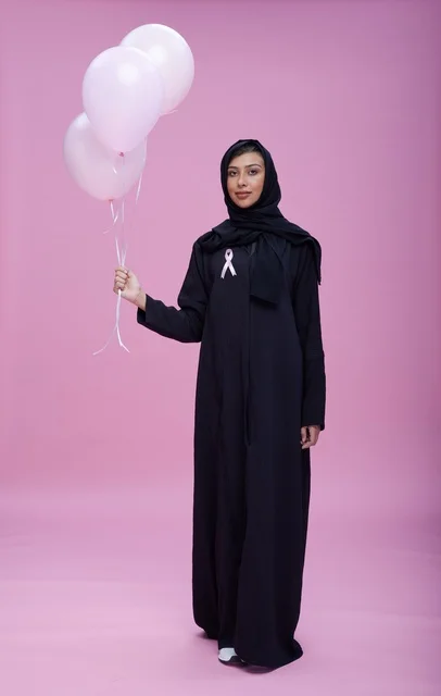 امرأة سعودية مع شريط التوعية بسرطان الثدي وبالونات