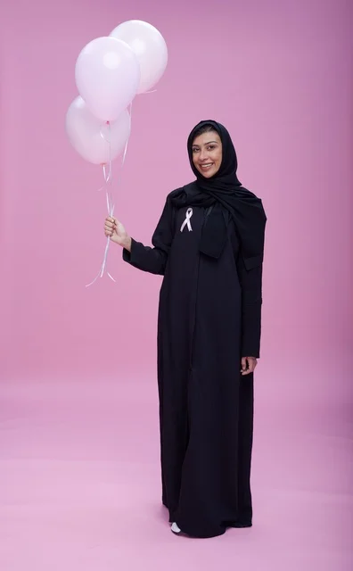 امرأة سعودية تحمل بالونات للتوعية بسرطان الثدي