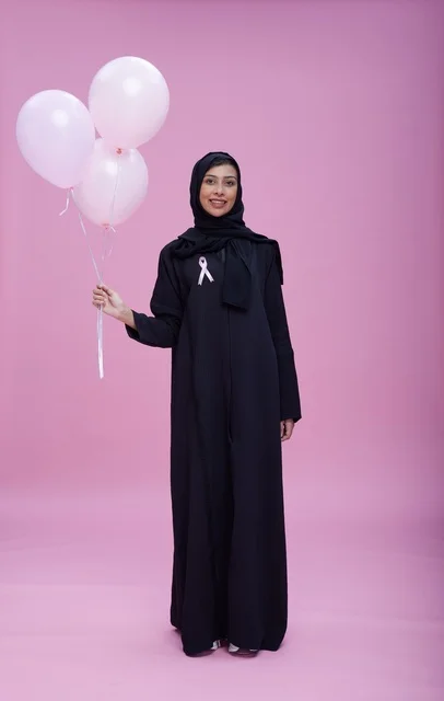 امرأة سعودية تدعم التوعية بسرطان الثدي مع بالونات وردية