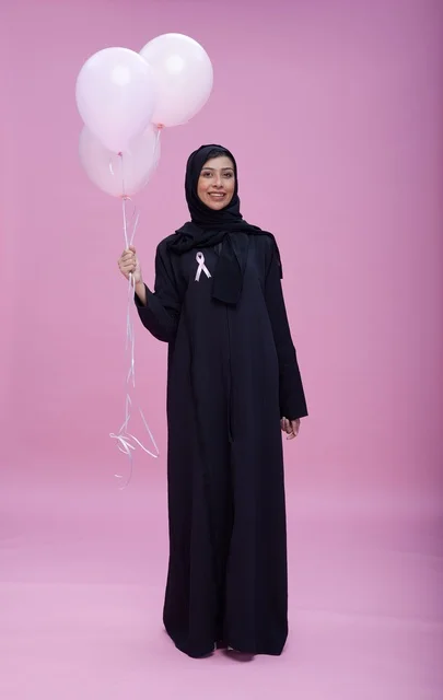 امرأة سعودية مع بالونات وردية للتوعية بسرطان الثدي