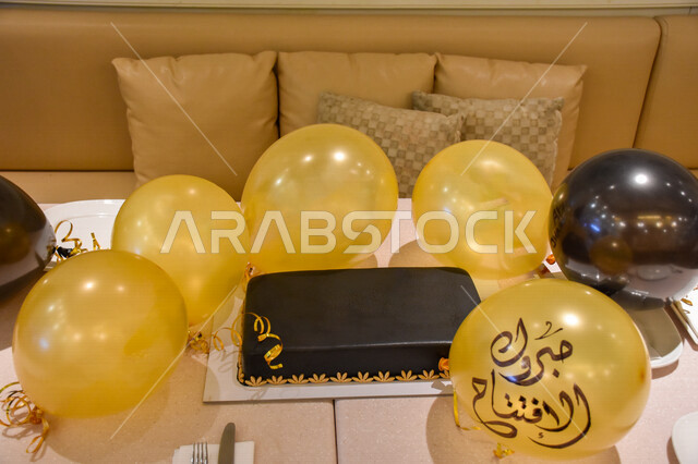 صورة لقالب كيك شوكولاتة مع بالونات الهيليوم الذهبية مع كتابة مبروك الافتتاح ، كتابة عربية ، خط اليد ، حفل افتتاح ، الإمارات العربية المتحدة ، احتفالات بمناسبة الإفتتاح ، أعياد ومناسبات ، مفاجأة ، مناسبات سعيدة
