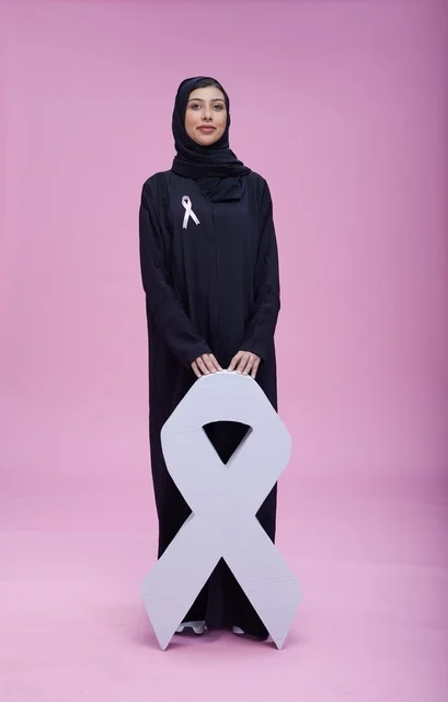 امرأة سعودية مع رمز التوعية بسرطان الثدي خلفية وردية