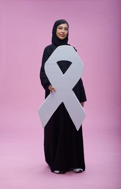 امرأة سعودية تمسك رمز التوعية بسرطان الثدي