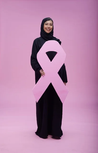 امرأة سعودية تمسك بشعار التوعية بسرطان الثدي