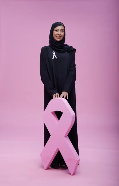 امرأة سعودية مع رمز التوعية بسرطان الثدي الوردي