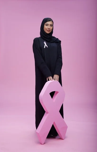 امرأة سعودية مع شعار التوعية بسرطان الثدي