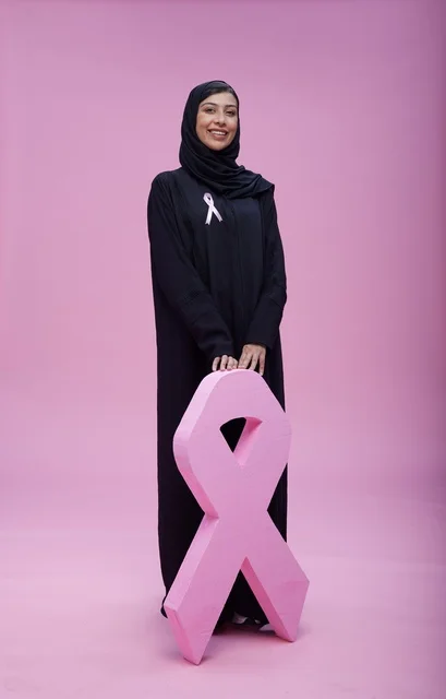 Saudi woman pointing at breast cancer awareness ribbon