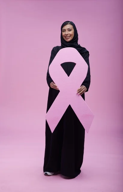 امرأة سعودية تحمل شعار التوعية بسرطان الثدي في استوديو