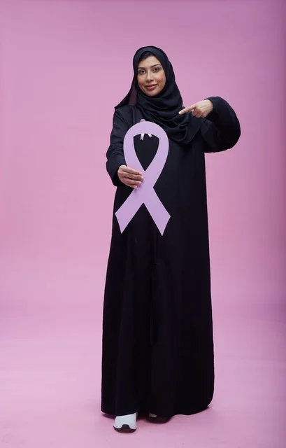 امرأة سعودية تحمل شعار التوعية بسرطان الثدي بخلفية وردية