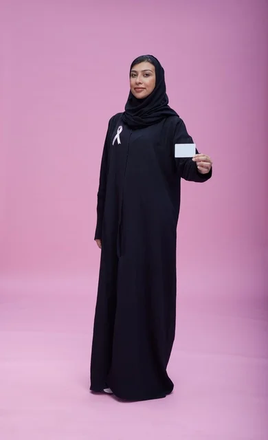 امرأة سعودية تحمل بطاقة توعية بسرطان الثدي