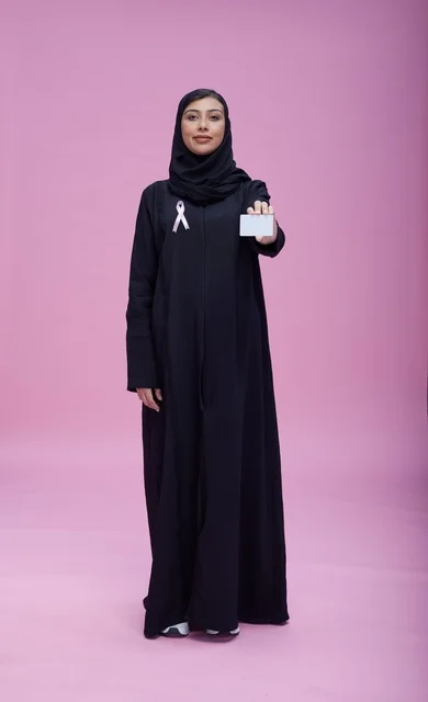 امرأة سعودية تحمل بطاقة توعية بسرطان الثدي