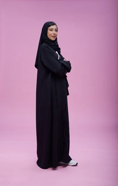 امرأة سعودية بالعباءة للتوعية بسرطان الثدي بخلفية وردية