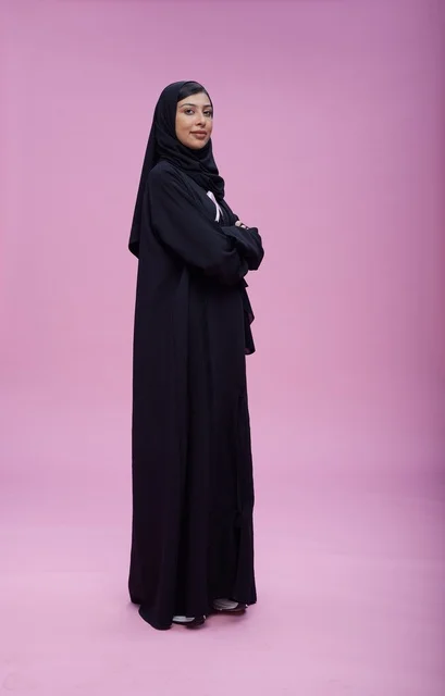 امرأة سعودية بالعباءة السوداء على خلفية وردية