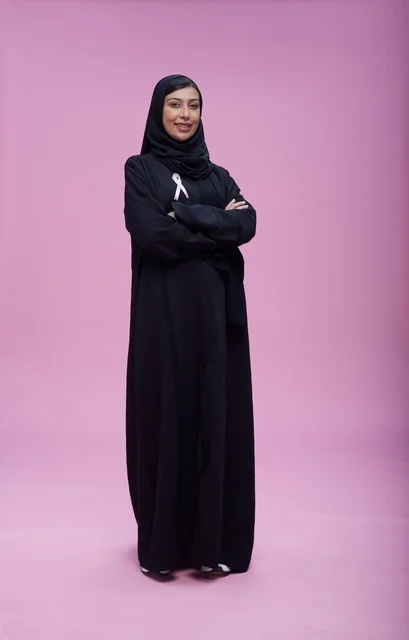 امرأة سعودية تدعم التوعية بسرطان الثدي بخلفية وردية