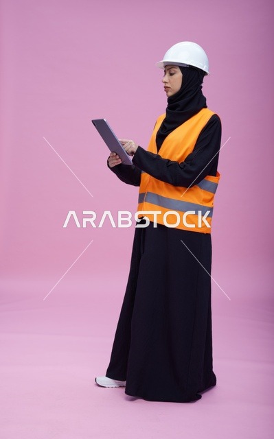 مهندسة سعودية مع جهاز لوحي بخلفية وردية