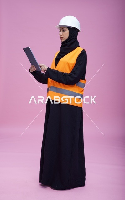 مهندسة سعودية مع جهاز لوحي بخلفية وردية
