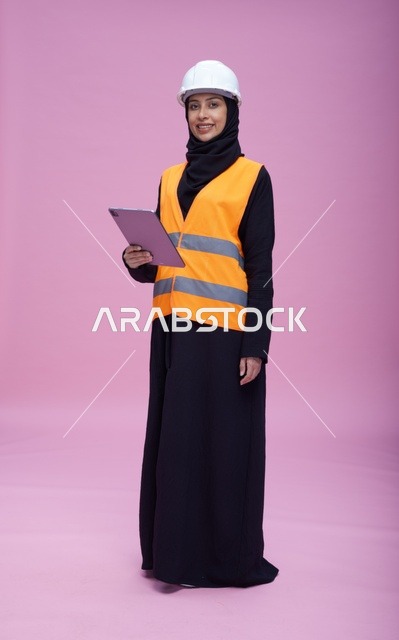 مهندسة سعودية مع جهاز لوحي بخلفية وردية