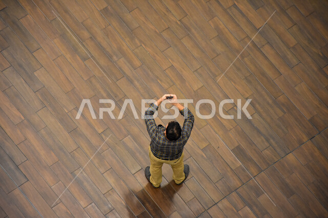 A picture from above of a tourist man taking a memorial selfie using a mobile phone, using modern technical devices, using social media, live broadcasting, video calling