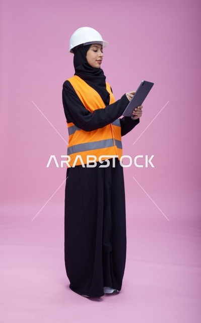 Saudi Female Engineer Using Tablet on Pink Background