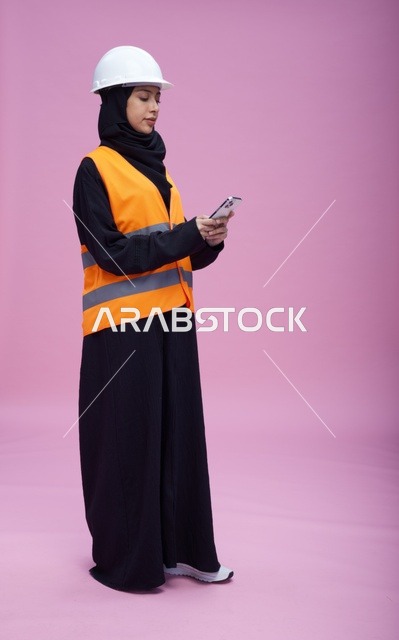 Saudi Female Engineer in Safety Vest Using Smartphone