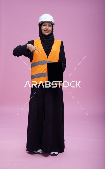 مهندسة سعودية تحمل جهاز لوحي بخلفية وردية