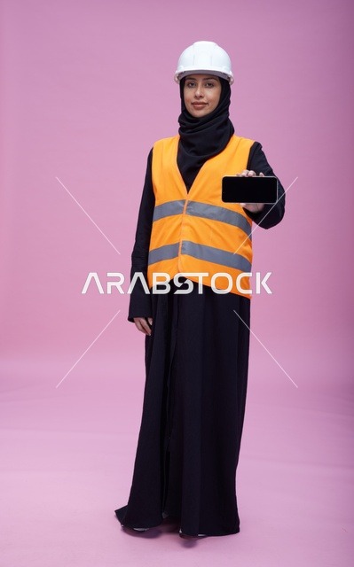مهندسة سعودية تحمل هاتف ذكي بخلفية وردية